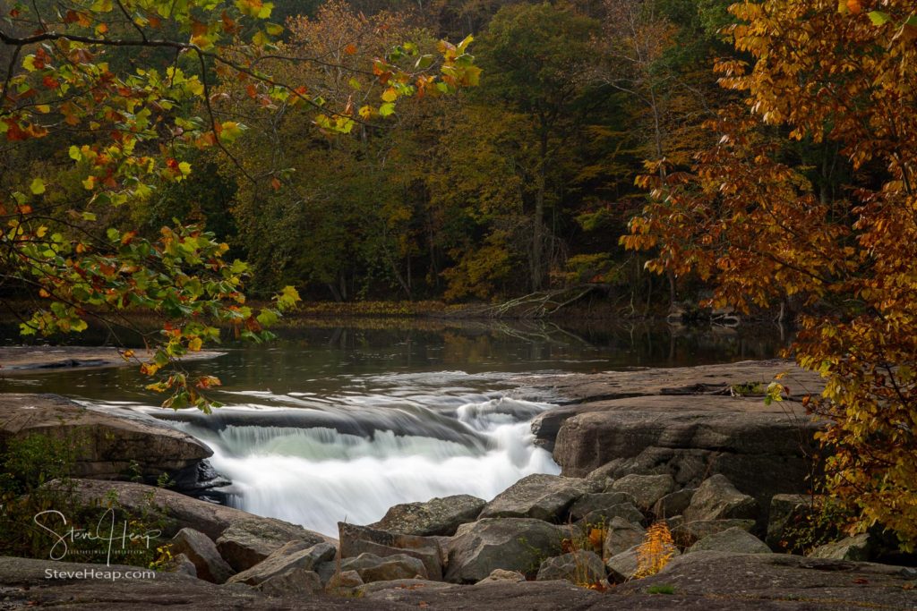 Small waterfall at Valley Falls State park in WV framed by autumn leaves