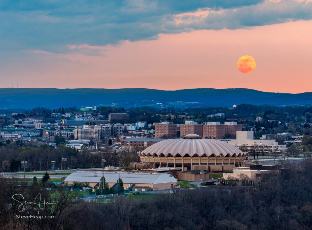 Super pink harvest moon rises above the coliseum arena on the Evansdale campus of WVU university on April 7, 2020. Prints available at this link