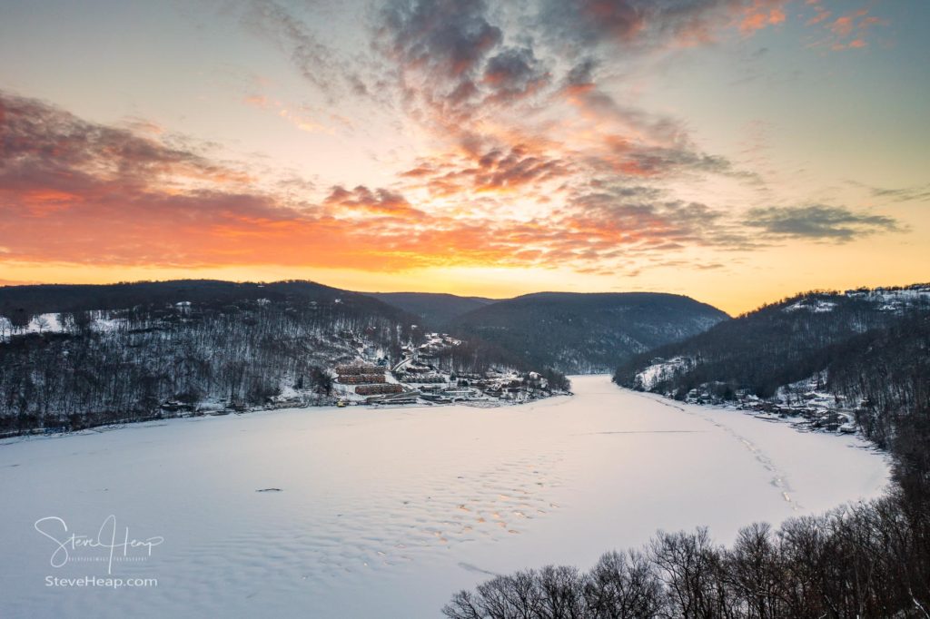 Aerial drone panorama of a spectacular sunrise over the frozen and snow-covered Cheat Lake looking upriver into the gorge near Morgantown, West Virginia