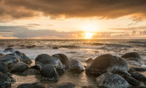 Sun setting over the Pacific ocean and worn rocks from Ke'e Beach on north of Kauai, Hawaii