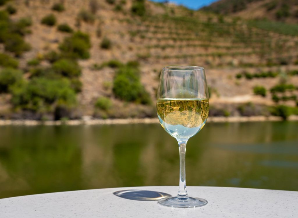 Glass of white wine for tasting on deck of cruise boat on the river in the Douro valley in Portugal. Prints available in my store
