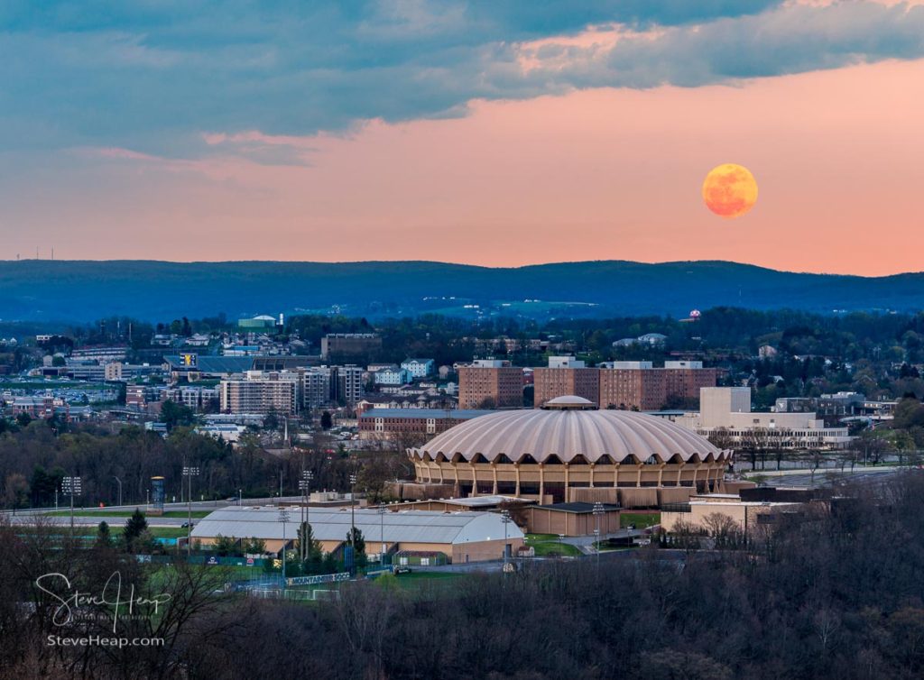 Super pink harvest moon rises above the coliseum arena on the Evansdale campus of WVU university on April 7, 2020. Prints available here