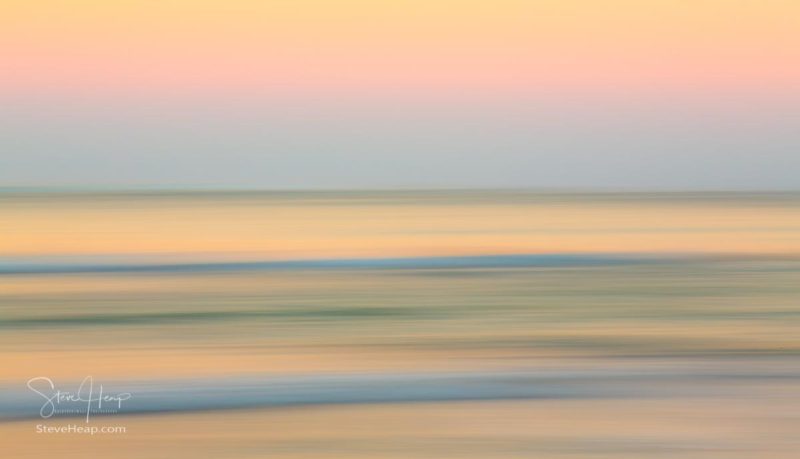 Sideways panning across the ocean reflecting the soft light of sunrise in Hawaii