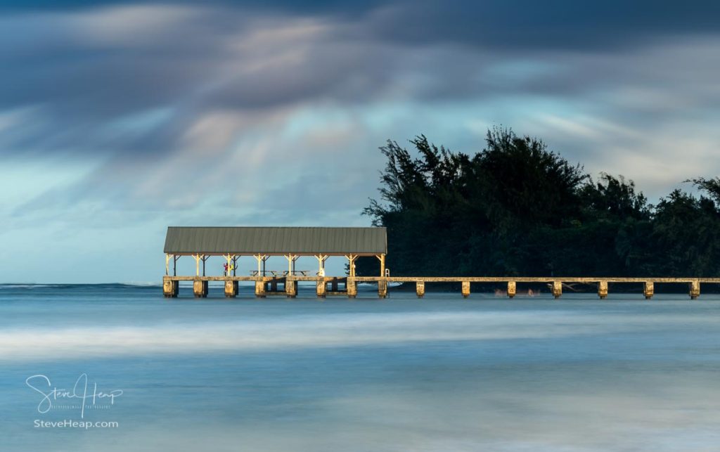 Sunrise lights the dawn sky above Hanalei Pier with long duration exposure to blur waves near Hanalei, Kauai. Prints in my online store