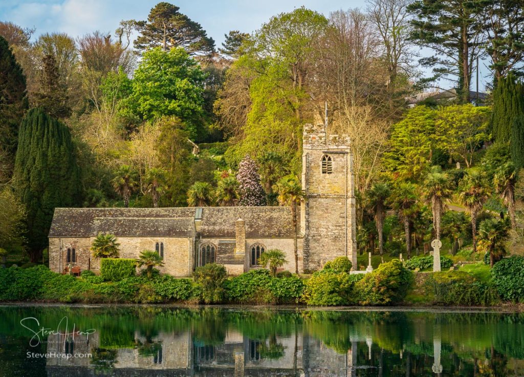 Pretty little parish church of St Just in Roseland near Truro in Cornwall UK reflected in the river at high tide. Prints available in my store