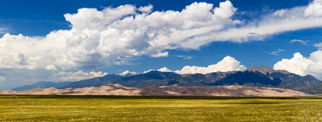 Wide high resolution stitched panorama of the dunes at Great Sand Dunes National Park in Colorado with the mountains behind. Unusual to see clouds over the sand. Prints available in my store