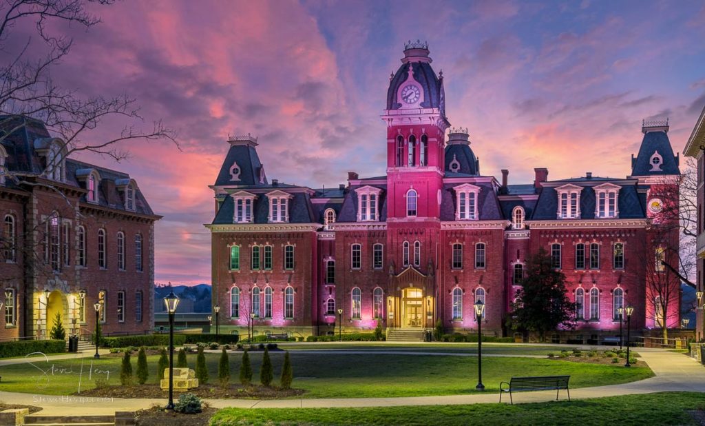 Dramatic image of Woodburn Hall at West Virginia University or WVU in Morgantown WV as the sun sets behind the illuminated historic building. Prints here