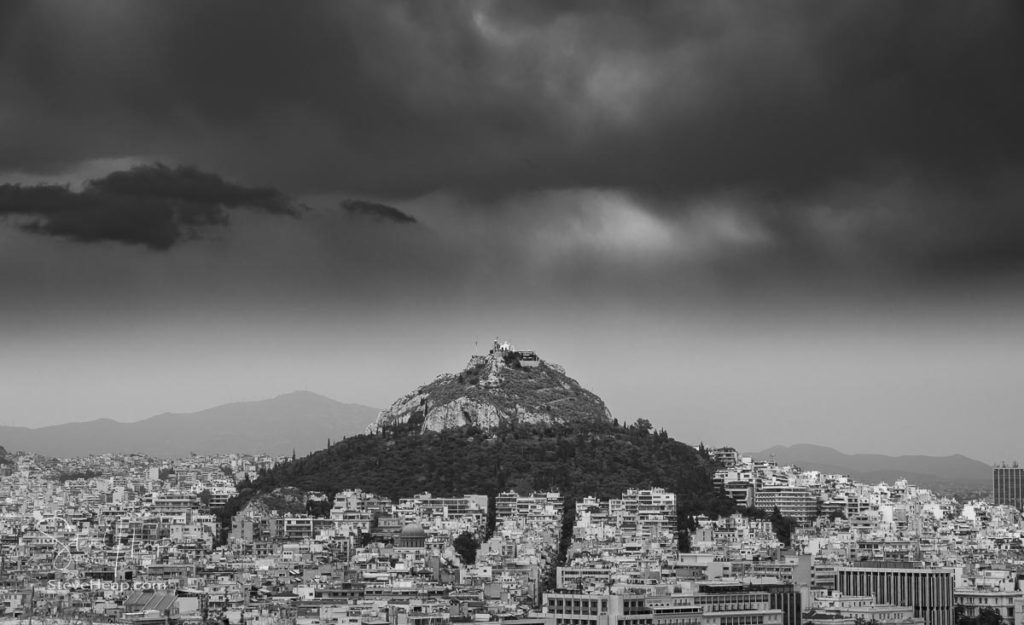 Black and white view of the storm clouds above Lycabettus hill with the city of Athens surrounding it. Prints available in my store
