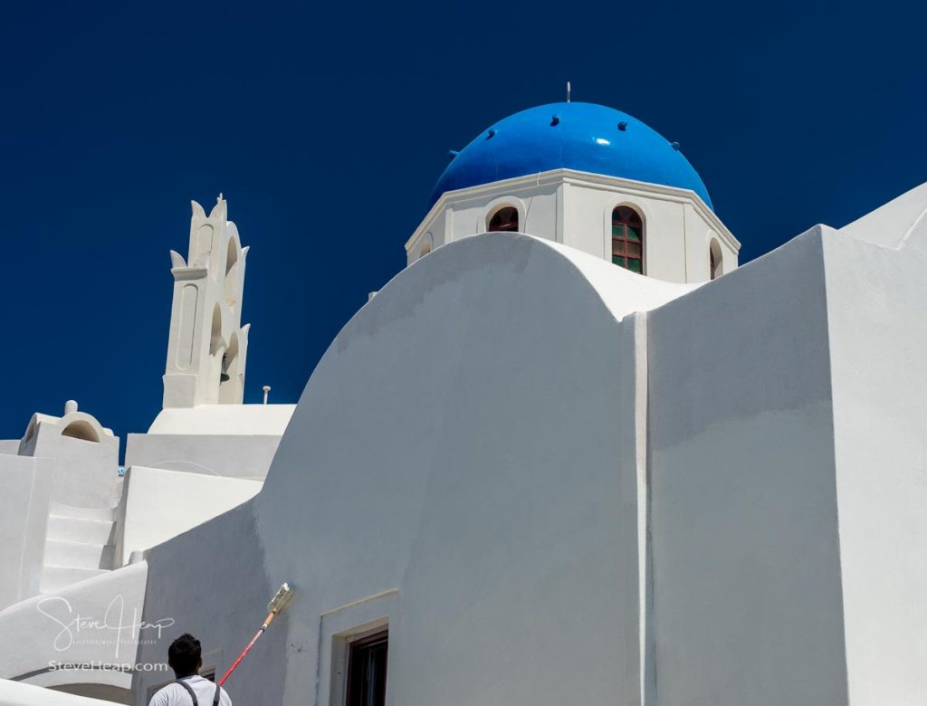 White paint being applied by roller to traditional house in Santorini