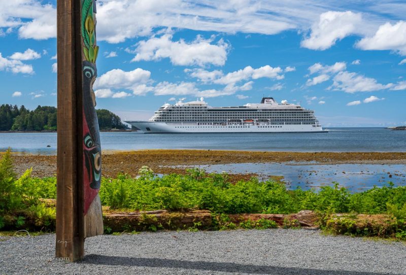 Sitka, AK - 8 June 2022: Totem pole displayed in the Sitka National Historical Park with cruise ship