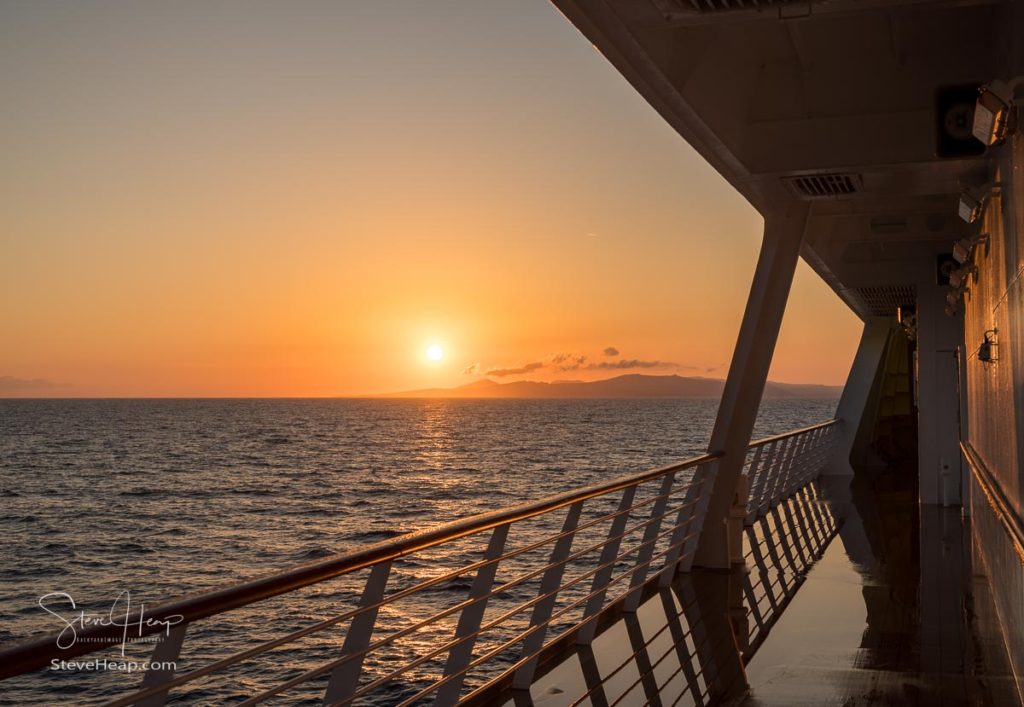 Approaching Santorini island as the sun rises over the ocean on the lower deck of the Viking Star cruise ship