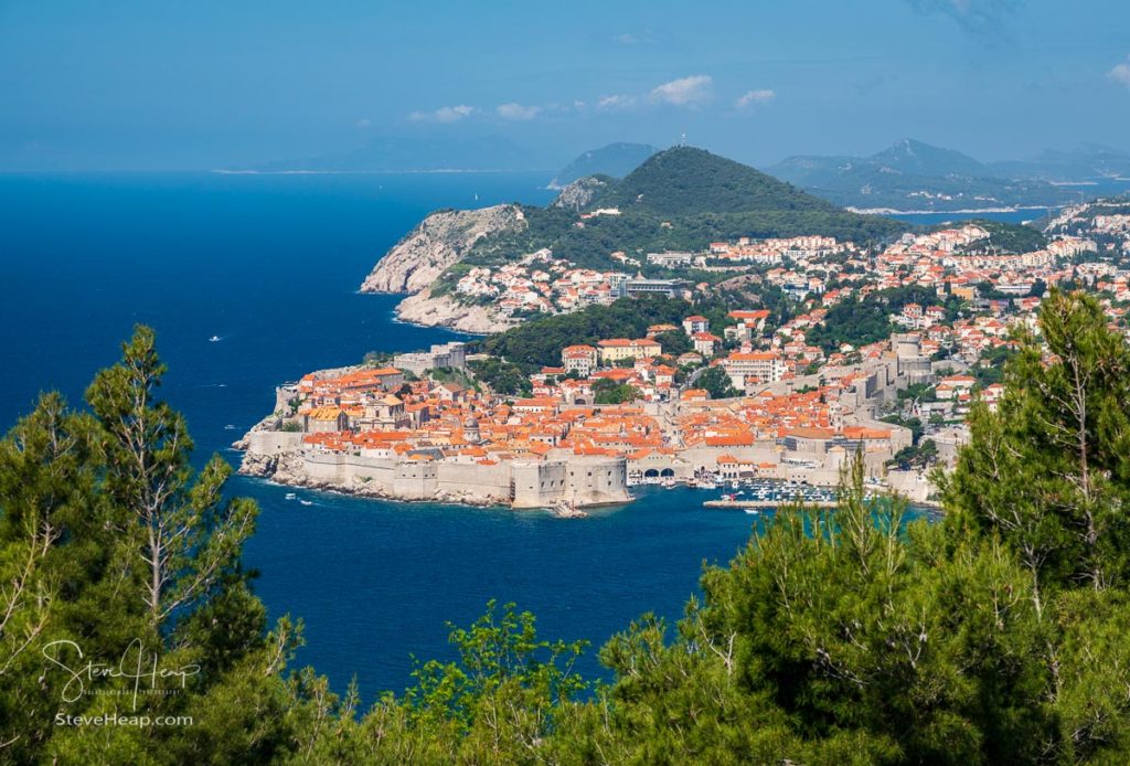 Trees frame an aerial shot of the old town of Dubrovnik and the city walls in Croatia. Prints in my online store