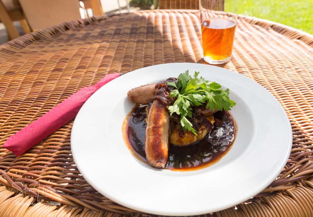 Traditional sausage and mash with gravy served outdoors with beer in English pub