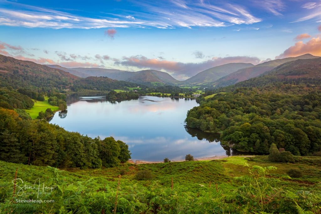 Overlook of the lake at Grasmere in Lake District at sunrise as sun lights up the mountains. Prints available in my store