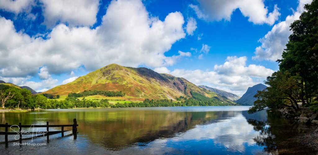 Wide panorama of the mountains reflecting into the calm waters of Buttermere in English Lake District. Prints in my store