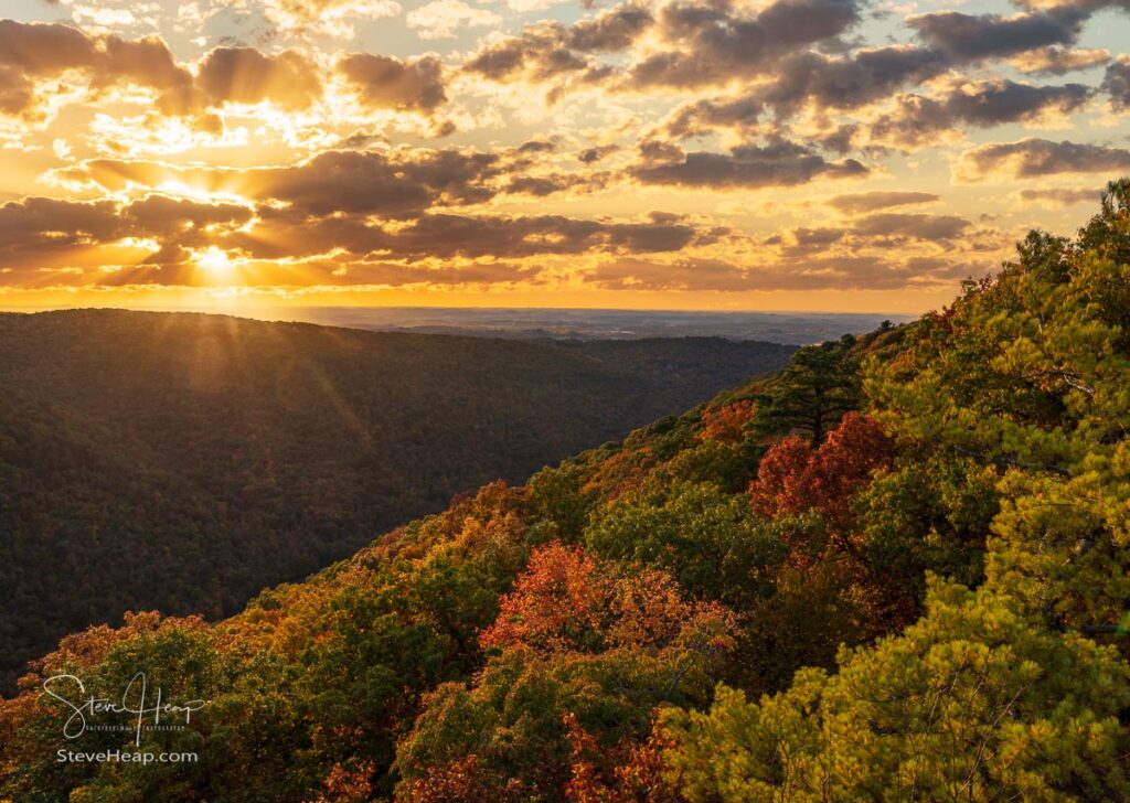 Sun setting behind clouds illuminating the fall colors from Coopers Rock