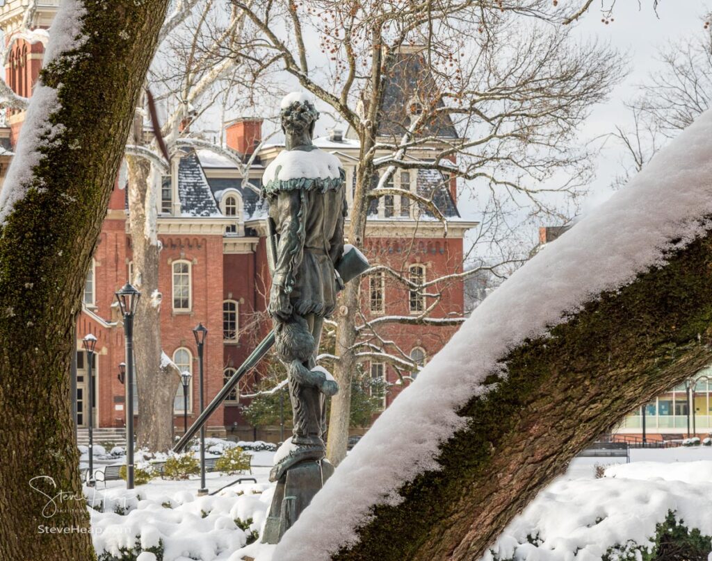 Famous WVU mascot, The Mountaineer, surveys the historic Woodburn Hall. Nicely framed by snow covered trees to make a perfect graduation gift for a graduating student from the university