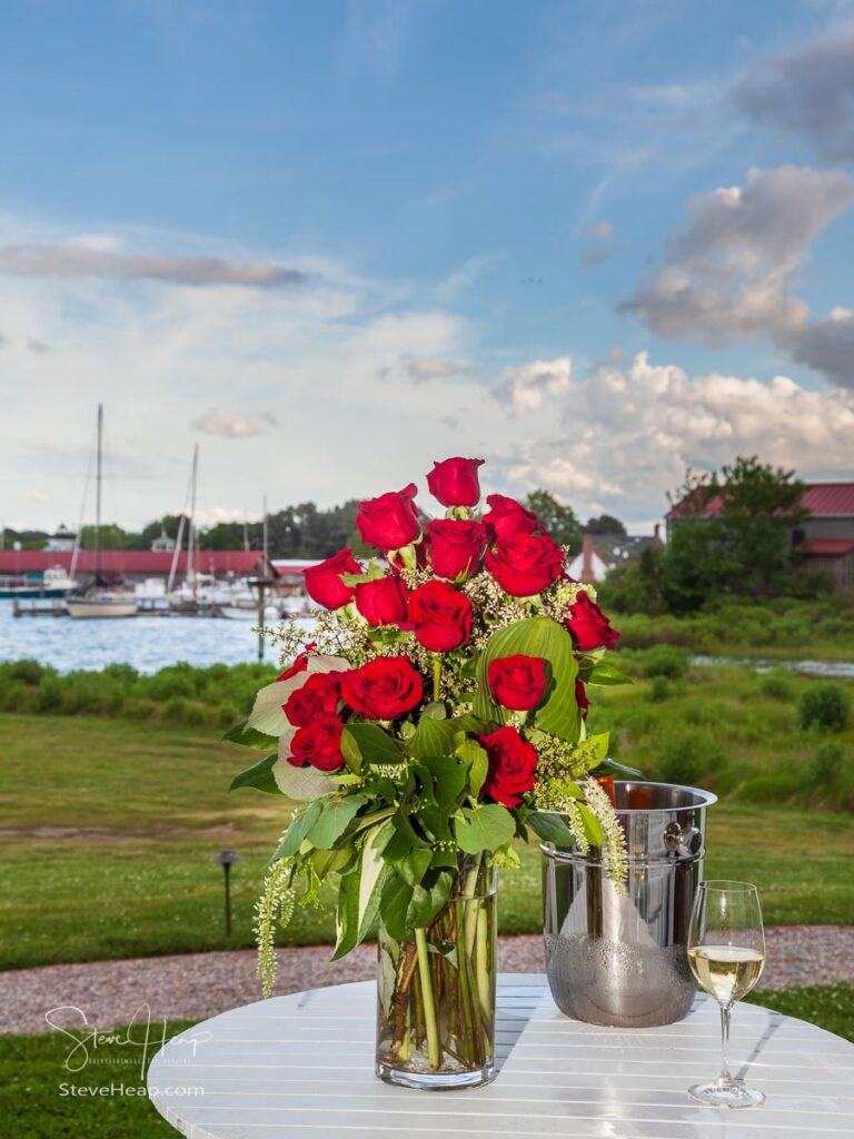 Bunch of red roses in vase on patio table with white wine in harbor setting in St Michaels, MD
