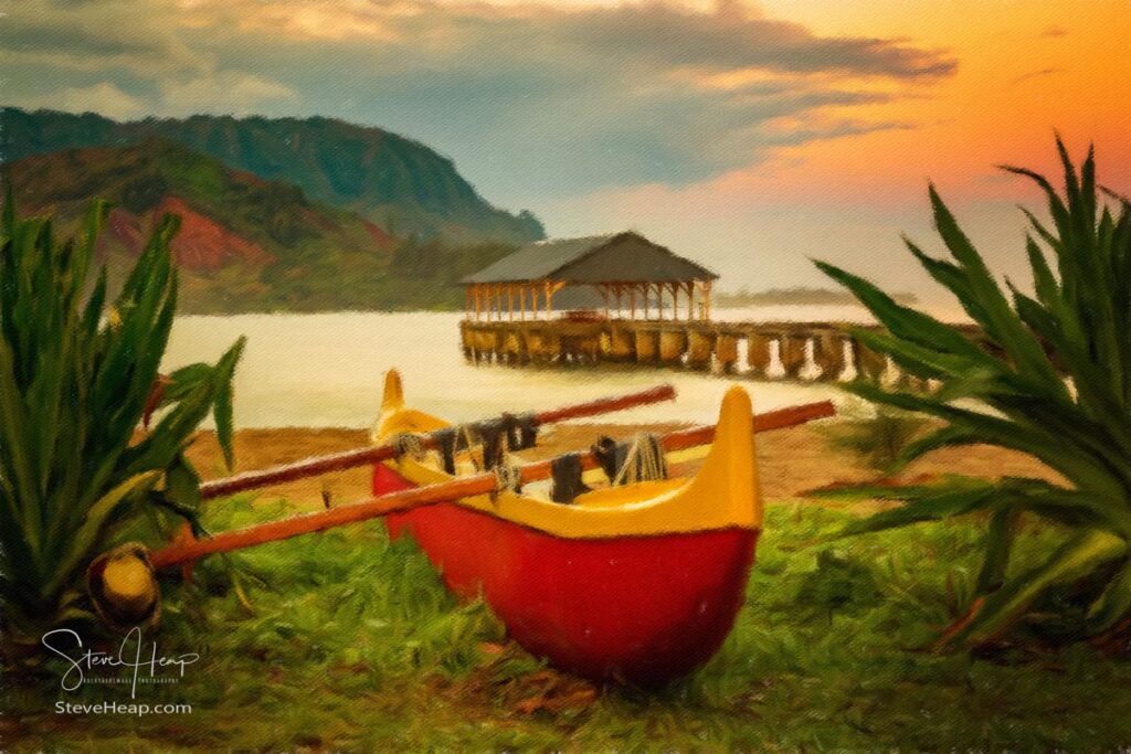 Red and yellow Hawaiian canoe with outrigger on the beach at Hanalei pier at dawn as the sun lights the sky over Na Pali mountains