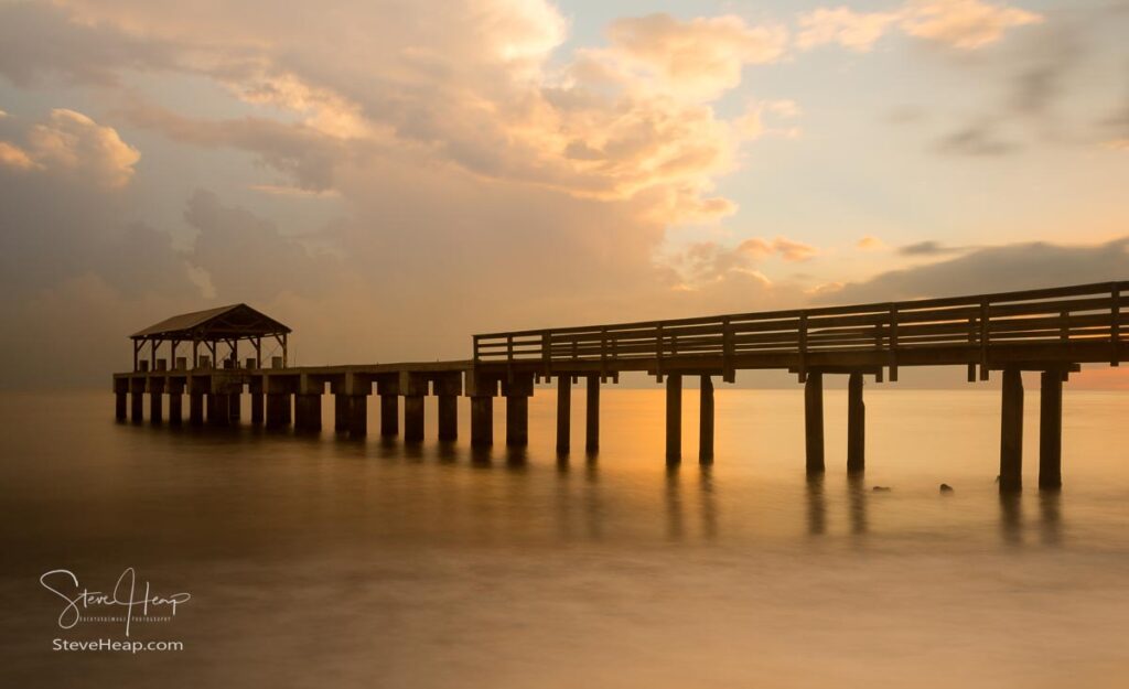 Long exposure image of Waimea pier at sunset blurs the ocean and bathes the structure in the warm glow of the setting sun. Prints in my online store