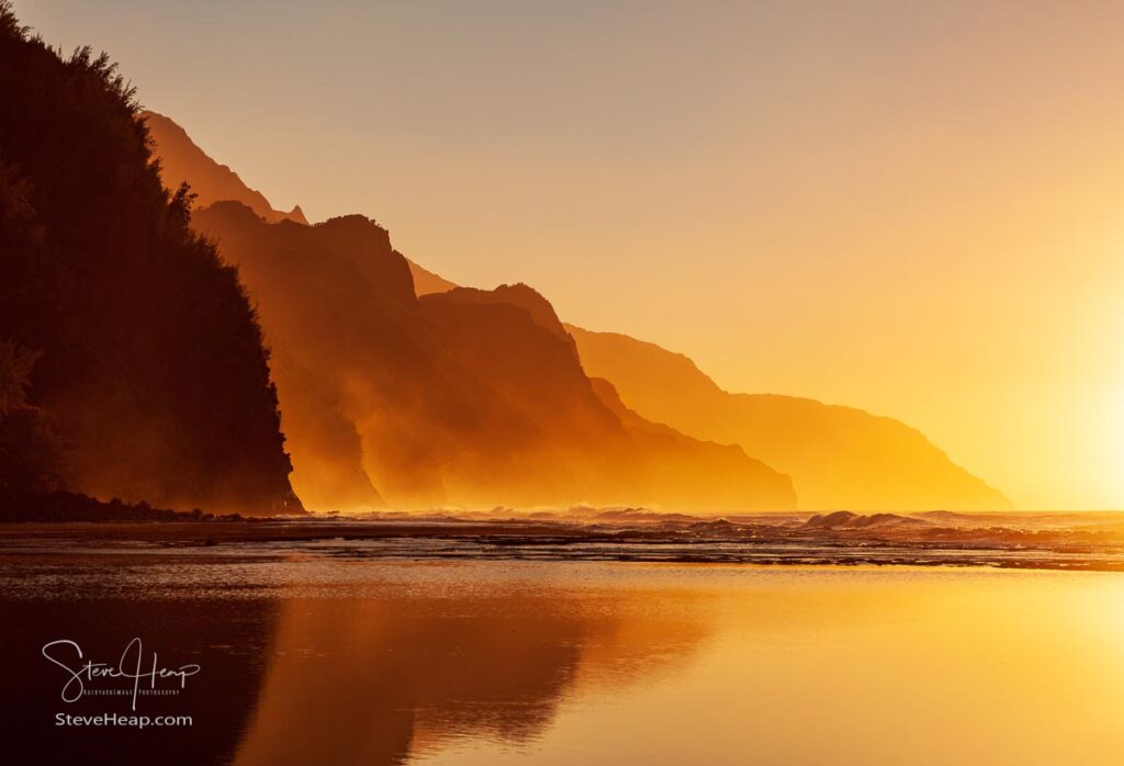 Na Pali coast by Ke'e beach at sunset with the sunlight looking as though the mountains are boiling with the haze and spray from the waves. Prints here