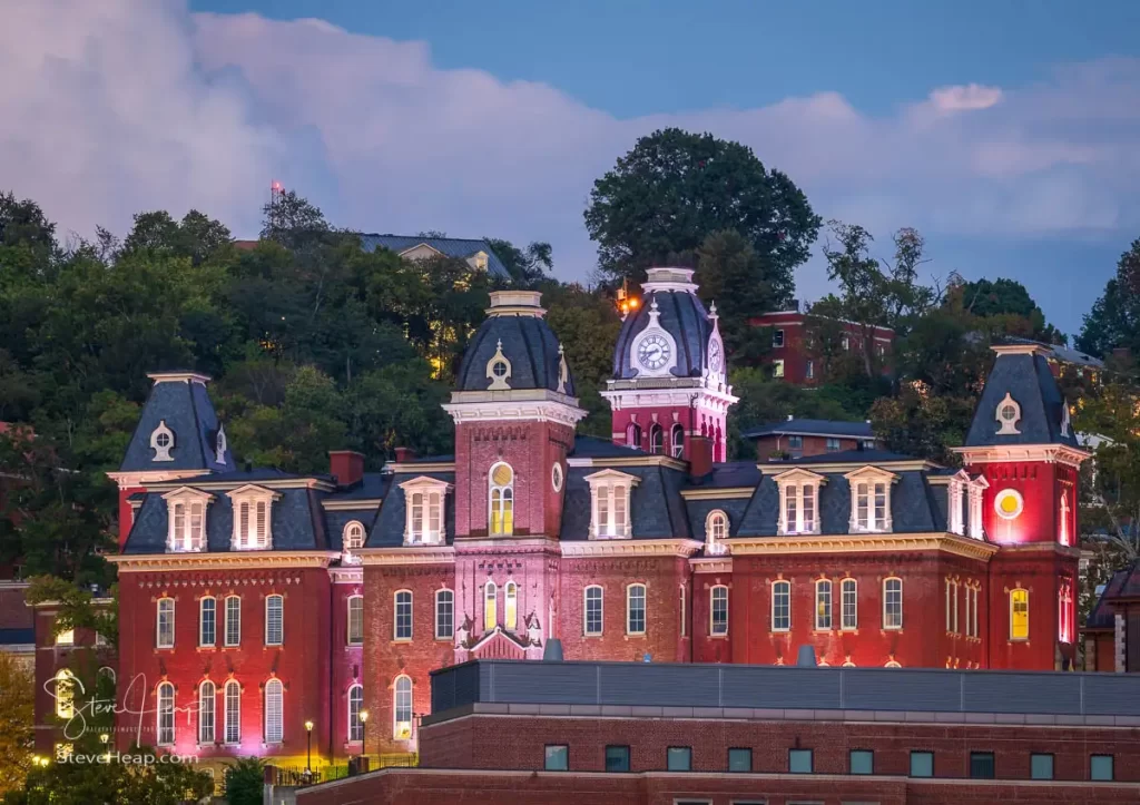 The illuminated facade of the old Woodburn Hall against the trees of downtown campus at West Virginia University in Morgantown
