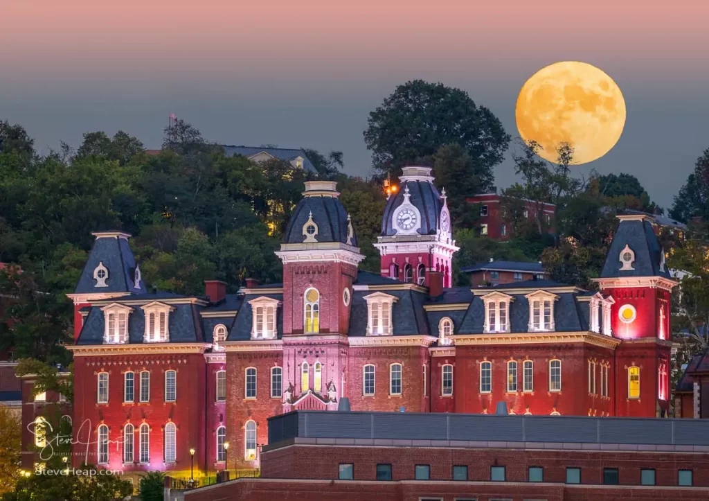 Imagined moonrise over the illuminated facade of the old Woodburn Hall against the trees of downtown campus at West Virginia University