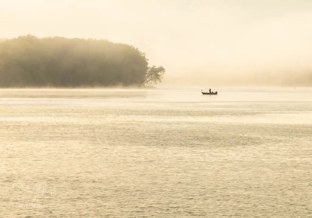 Lone fisherman casting his line in the Mississippi river with the swirling mists surrounding him in Dubuque, Iowa. Prints available in my store