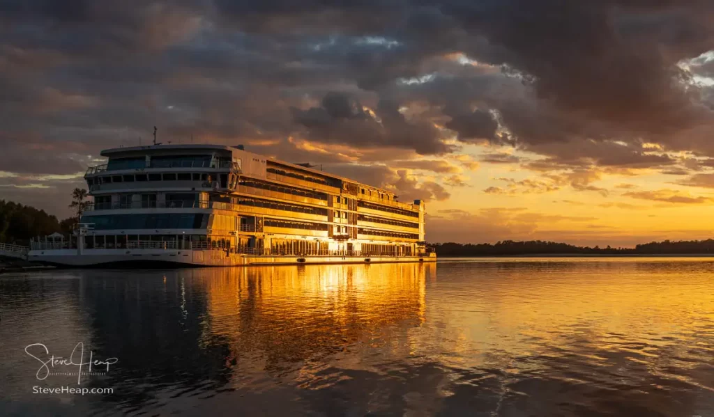 Sunset illuminates the Mississippi river and the Viking Mississippi cruise ship docked by the river bank at Vicksburg