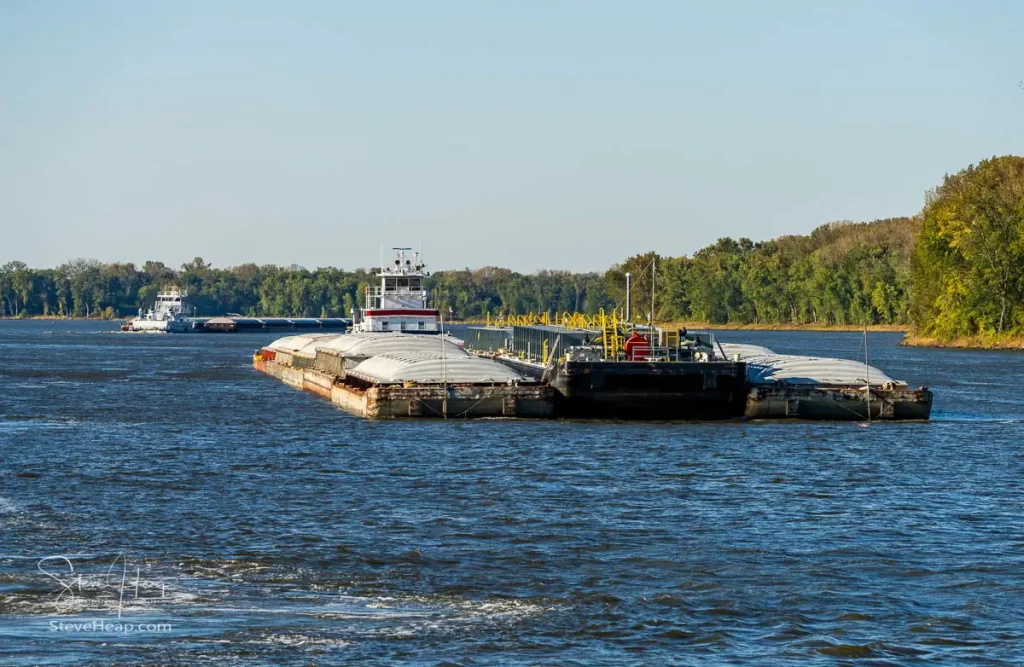 Tug boat pusher behind freight barges loaded with grain on Mississippi River