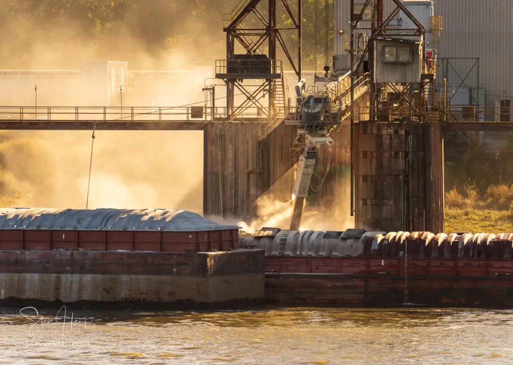 Rising sun illuminates the dust from filling the large river barges with grain in East St Louis, Illinois