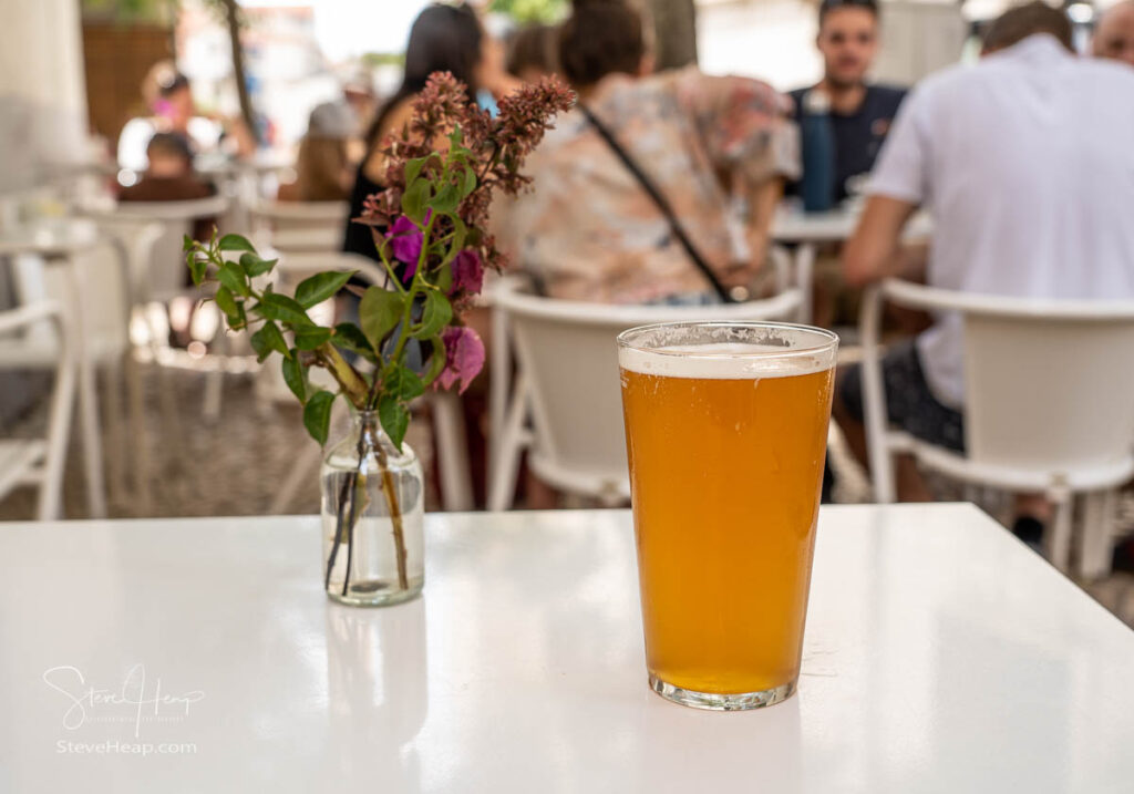 Focus on a cold glass of IPA beer with decorative flowers on white table in Lisbon bistro