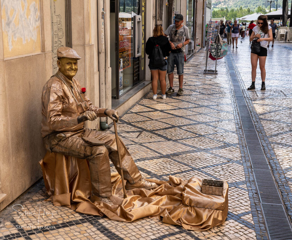 Living statue actor dressed in gold and playing part of an old tourist in the historic town of Coimbra in Portugal