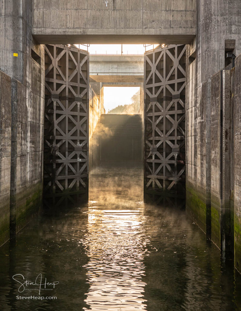 Solid wooden lock gates opening to show the mist from sunrise at the Crestuma Lever dam on River Douro in Portugal