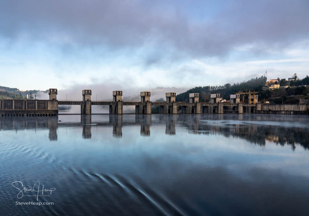 Solid structure of the Crestuma Lever dam on River Douro in Portugal reflected in calm water