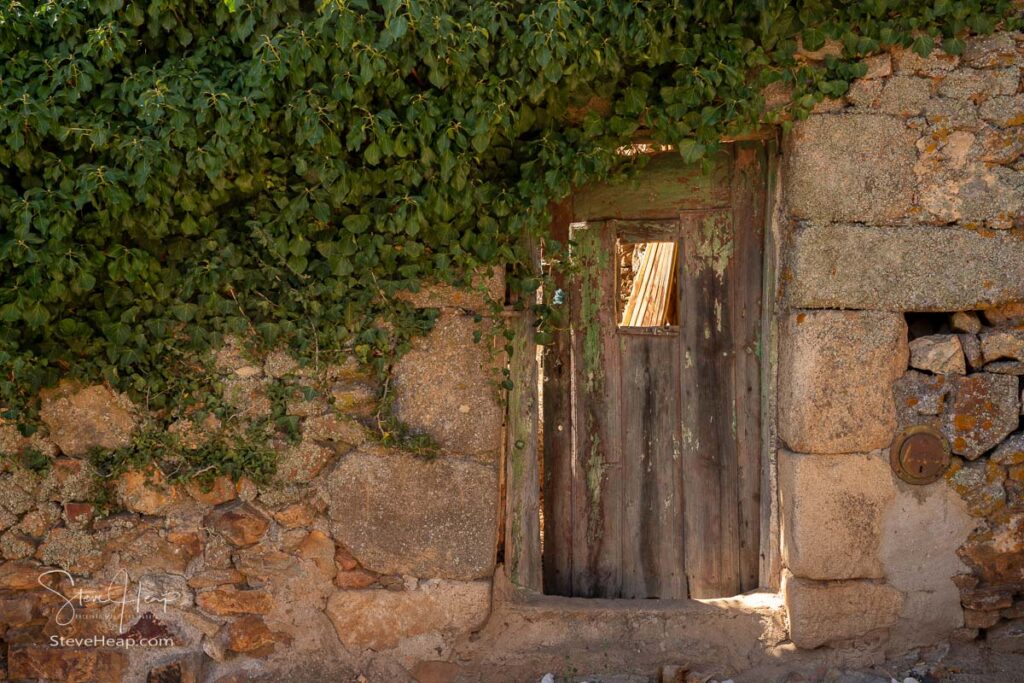 Wooden door opening into garden of stone house in the ancient town of Castelo Rodrigo in Portugal