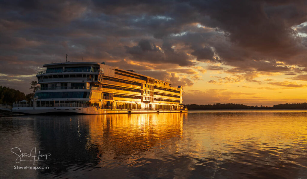 Vicksburg, MS - 25 October 2023: Viking Mississippi docked by bank as sunset cast golden glow on the boat and reflections