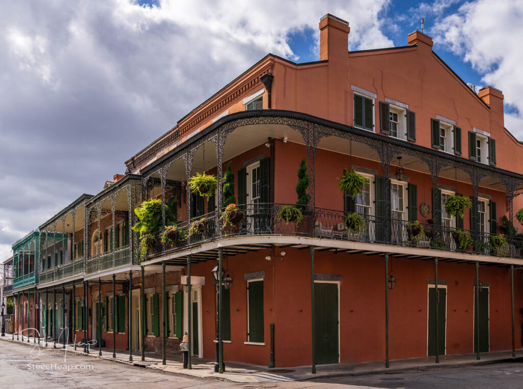 Hanging baskets on traditional New Orleans corner building in the French Quarter with wrought iron railings and balconies. Prints in my online store.