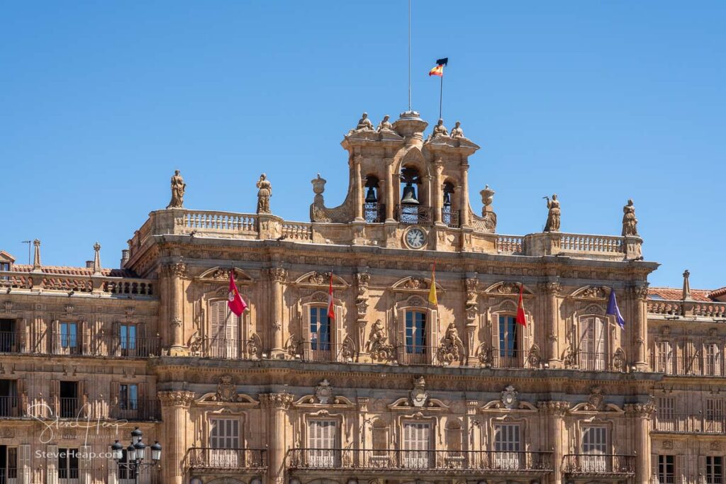 Flags fly over the windows of City Hall and clock tower in Plaza Mayor in Salamanca, Spain