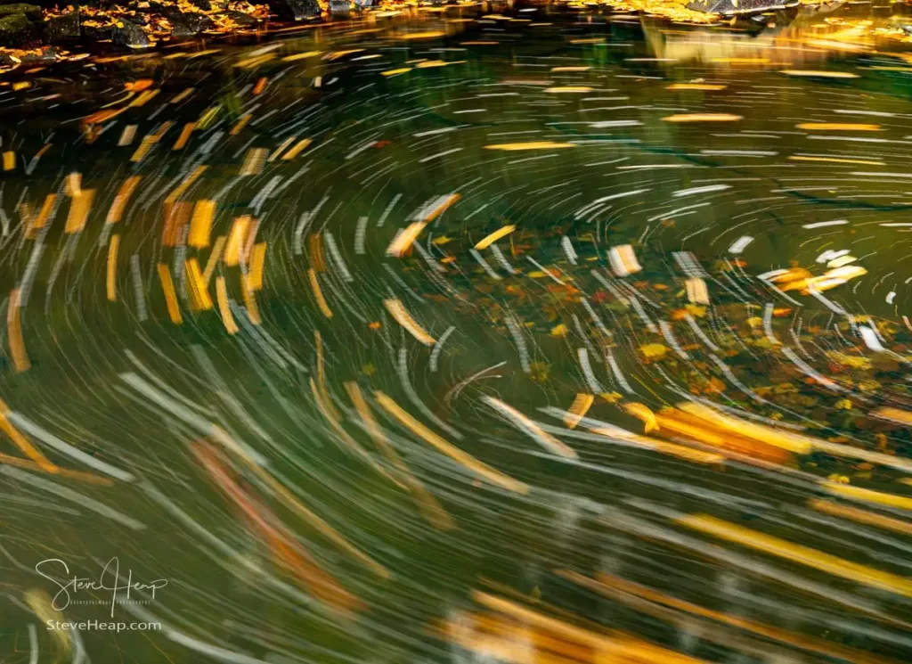 Swirling leaves in the river below waterfall into swimming hole with blurred motion on Deckers Creek running by Route 7 near Masontown in Preston County West Virginia