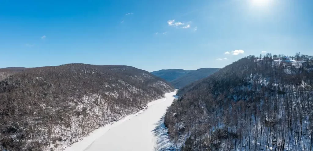 Aerial drone view of the snow-covered and frozen Cheat River flowing through the mountains towards the lake near Morgantown in West Virginia