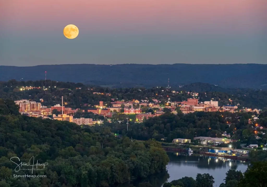 Moon rising over the hills surrounding Morgantown with the illuminated downtown campus of WVU above the Monongahela river