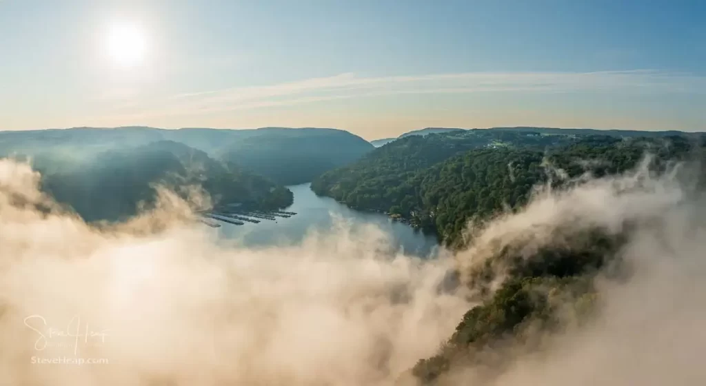 Unusual mist and fog forming over Cheat Lake with aerial view across the lake to marinas and to the Cheat River entering the scene