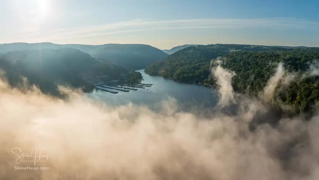Unusual mist and fog forming over Cheat Lake with aerial view across the lake to marinas and to the Cheat River entering the scene
