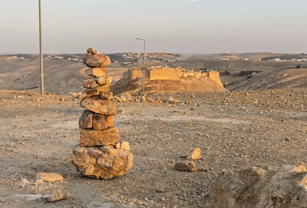 A balanced rock pile in the arid landscape near Shonak Castle at sunset, evoking a sense of tranquility and nature.