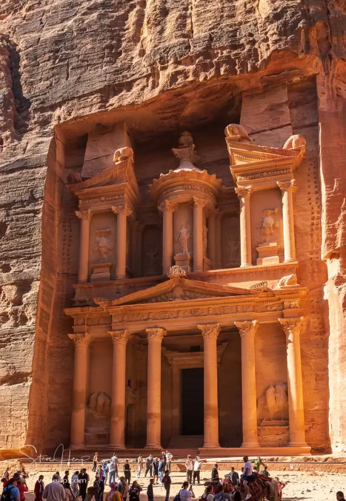Tourists at the carved facade of the Treasury building or Al-Khazneh in the ancient city of Petra