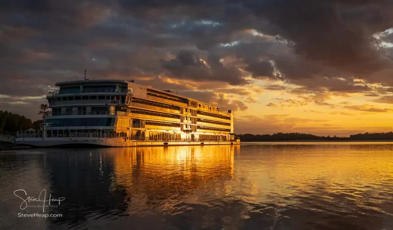 The Viking Mississippi docked by the side of the river with a gorgeous sunset illuminating the modern ship