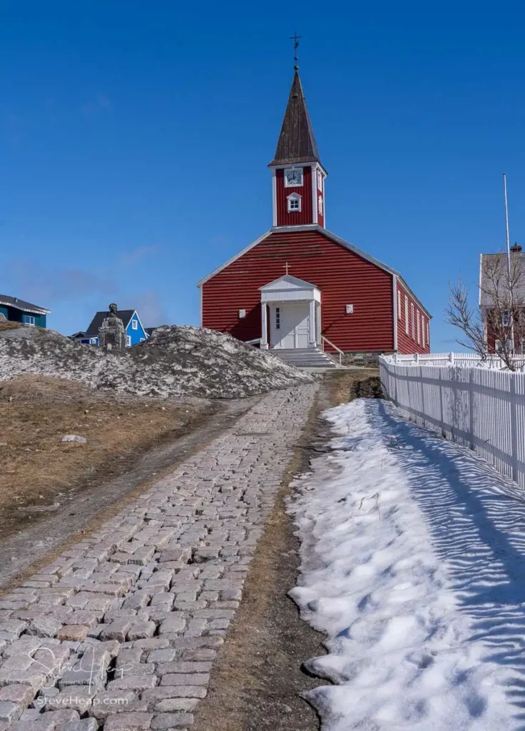 Snow covered pathway leads to traditional red wooden building of Church of our Saviour in Nuuk in Greenland
