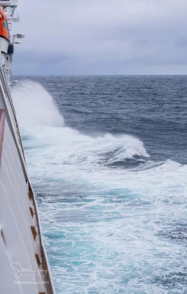 View down the side of the Viking Neptune cruise ship in arctic ocean going through high waves and strong winds
