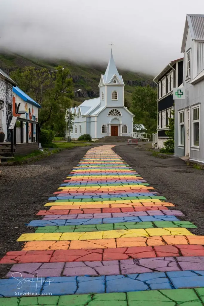 Famous Blue church surrounded by low clouds in Seydisfjordur in Iceland at the end of Rainbow Street